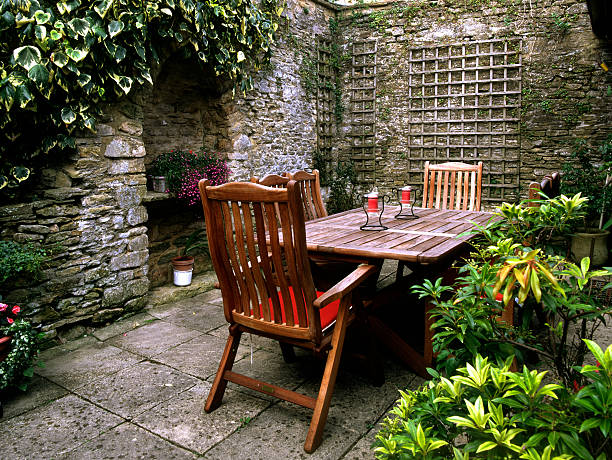 Small secluded garden patio, walls around, wooden tables and chairs